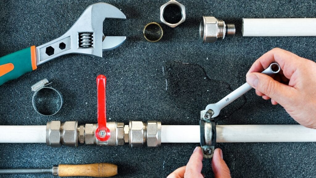 Plumber repairing a pipe valve with an adjustable wrench in Prescott
