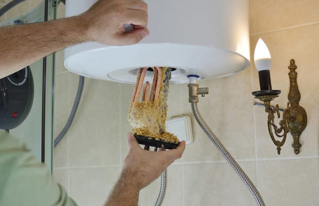 Technician removing mineral buildup from a water heater in Prescott