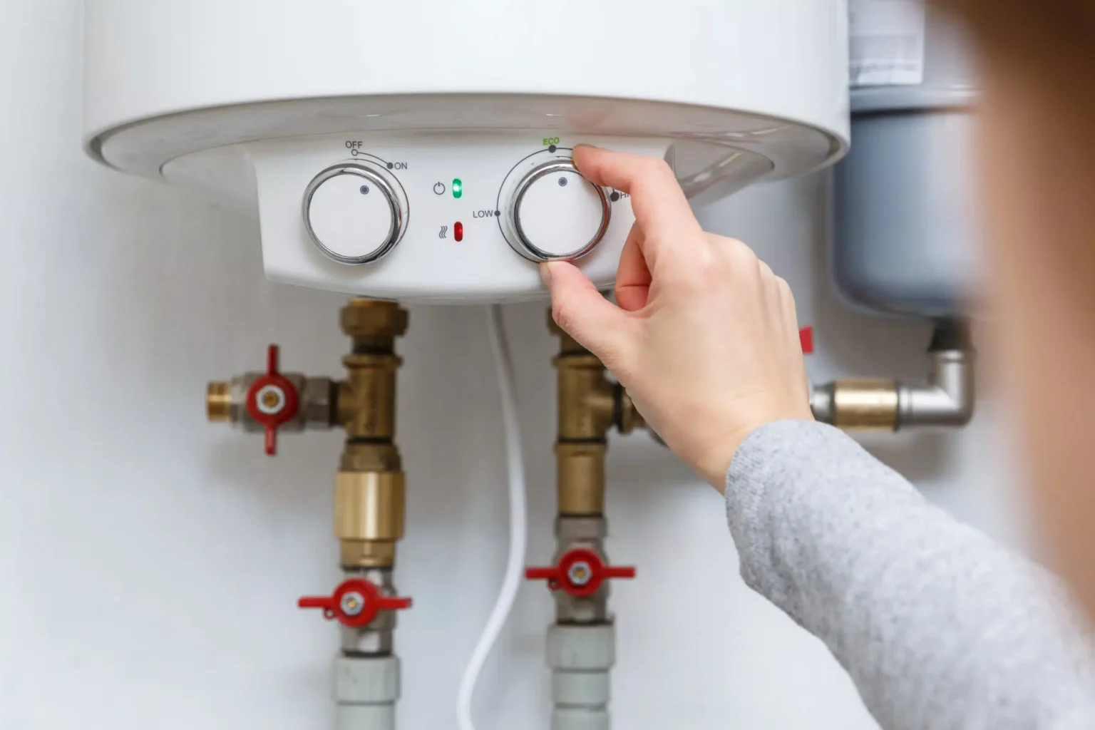 Homeowner adjusting the temperature controls on a water heater in Prescott